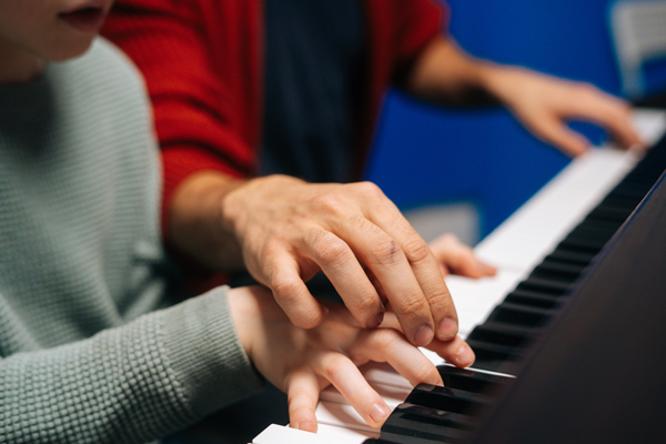 Closeup of piano instructor and students hands on keys